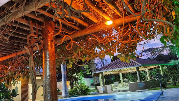 Ein überdachter Außenbereich mit einer Pergola, einem Pool und einem Pavillon im Hintergrund.