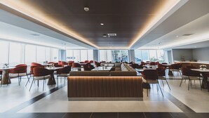 Un comedor amplio y moderno con techos altos, ventanas grandes y una zona de estar central.