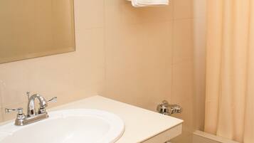 A bathroom with two sinks, a toilet, a trash bin, and a towel rack with towels.