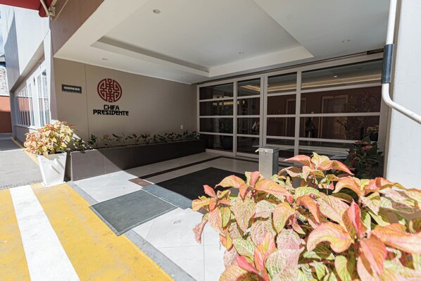 A hotel entrance with a sign reading "CHIFA PRESIDENTE" and a large glass door.