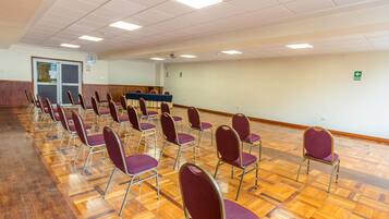 A conference room with rows of purple chairs, a blue table, and a wooden floor.
