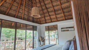 A bedroom with a wooden bed, large windows, and a thatched roof. - Zamna eco-lodge Tulum (Tulum)
