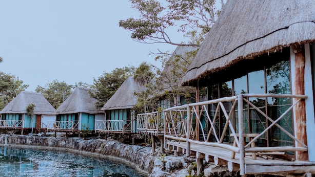 Overwater bungalows with thatched roofs and wooden walkways over water. - Zamna eco-lodge Tulum (Tulum)