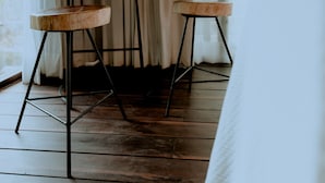 A room with a wooden dining table and two stools, a window with curtains, and a wooden floor. - Zamna eco-lodge Tulum (Tulum)