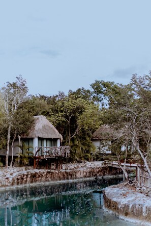 Un complexe hôtelier tropical doté d’une piscine, de bungalows aux toits de chaume et d’une végétation luxuriante.