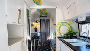 Un intérieur de camping-car compact comprenant un coin cuisine, un espace repas et un coin nuit.