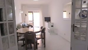 Ein Essbereich mit einem runden Tisch und Stühlen, einem Fernseher auf einem Schrank und einer Tür mit dekorativen Tellern.