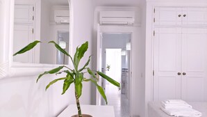Ein helles Badezimmer mit einem Blumentopf, weißen Handtüchern und einem Spiegel.