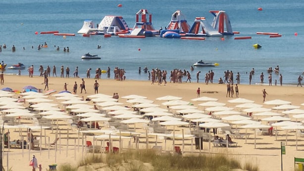 Ein Strand mit vielen Sonnenschirmen und Menschen.