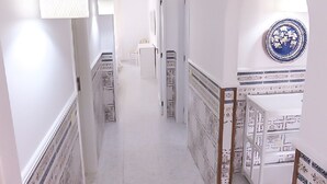 Ein Korridor mit gemusterten Fliesen, einer weißen Tür am Ende und einem dekorativen Teller an der Wand.