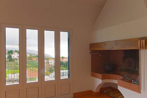 Um quarto com lareira de tijolos, varanda com vista para a cidade e uma grande janela com vista urbana.