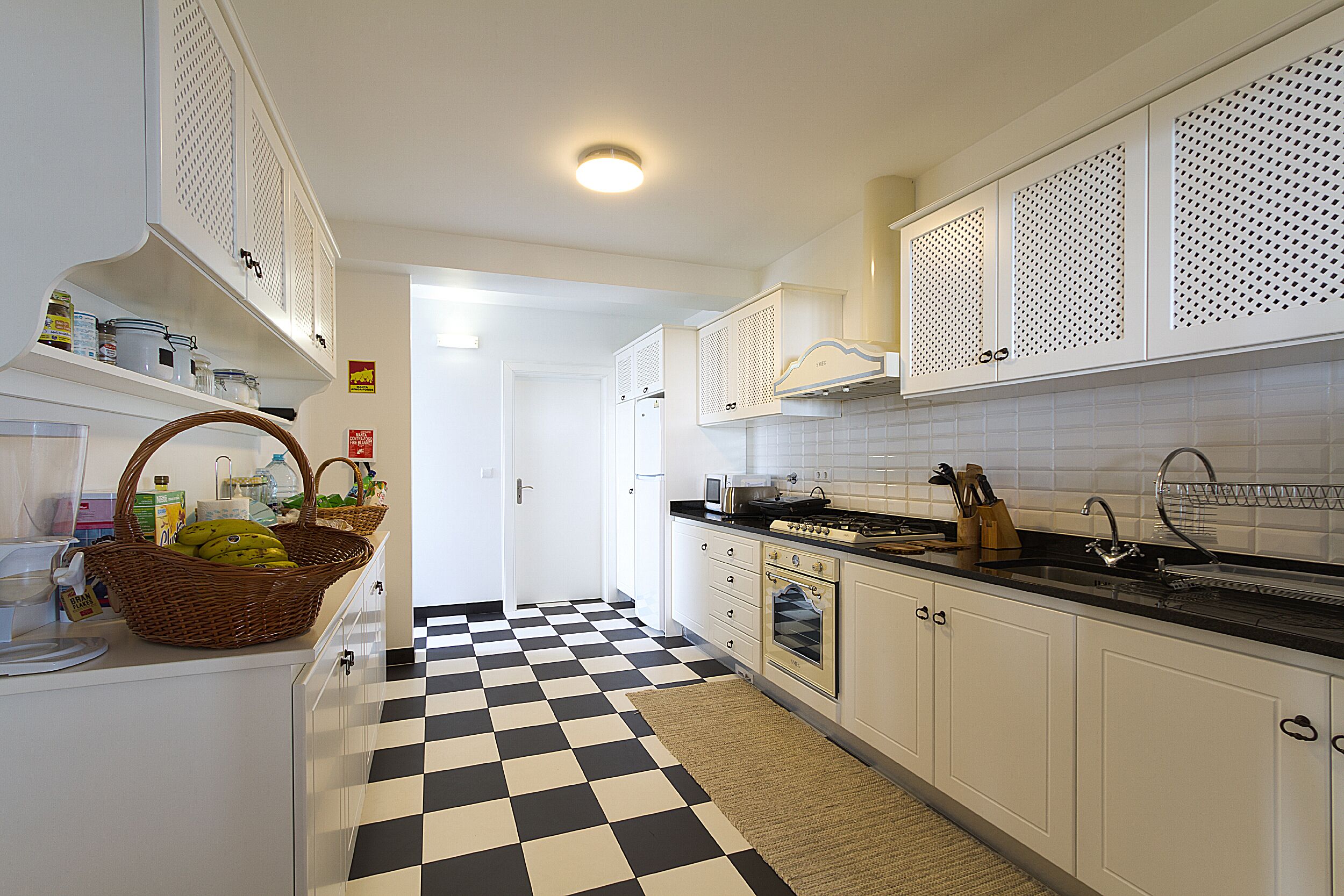 A kitchen with white cabinets, a checkered floor, and a microwave.