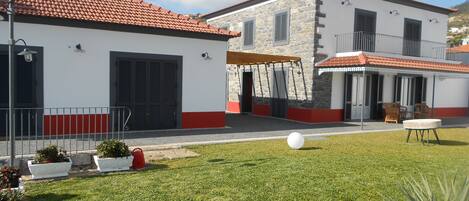 A courtyard with a lawn, a white spherical object, and a building with a red-tiled roof and stone walls.