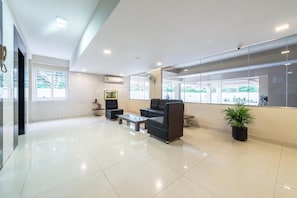 A modern lobby with a glass wall, seating area, and a potted plant.