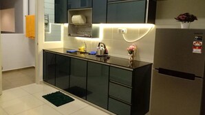 Una cocina moderna con armarios oscuros, un refrigerador de acero inoxidable y un horno empotrado.
