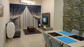 Una sala moderna con televisor, zona de estar y mesa de comedor.