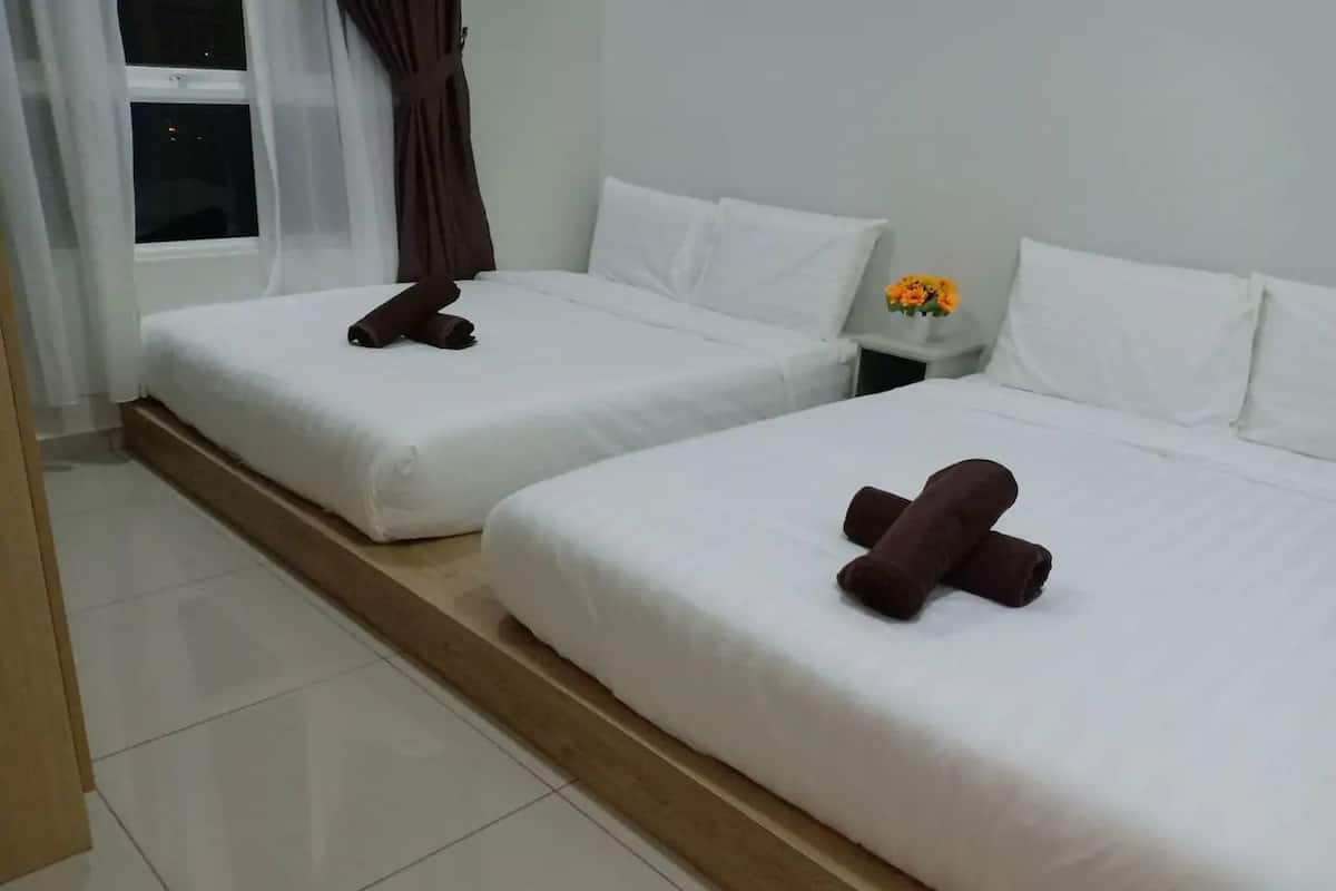 A hotel room with two beds, white bedding, and a nightstand with a vase of flowers.