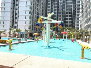 A swimming pool with colorful water features and a modern apartment building in the background. - BLeisure Parkland Homestay (Malacca City)