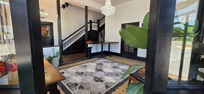 A staircase with a black railing and a chandelier, a patterned rug, and a potted plant. - The Clinton Inn (Clinton)