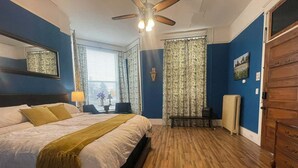 A bedroom with a bed, a ceiling fan, a radiator, and a wooden dresser. - The Clinton Inn (Clinton)