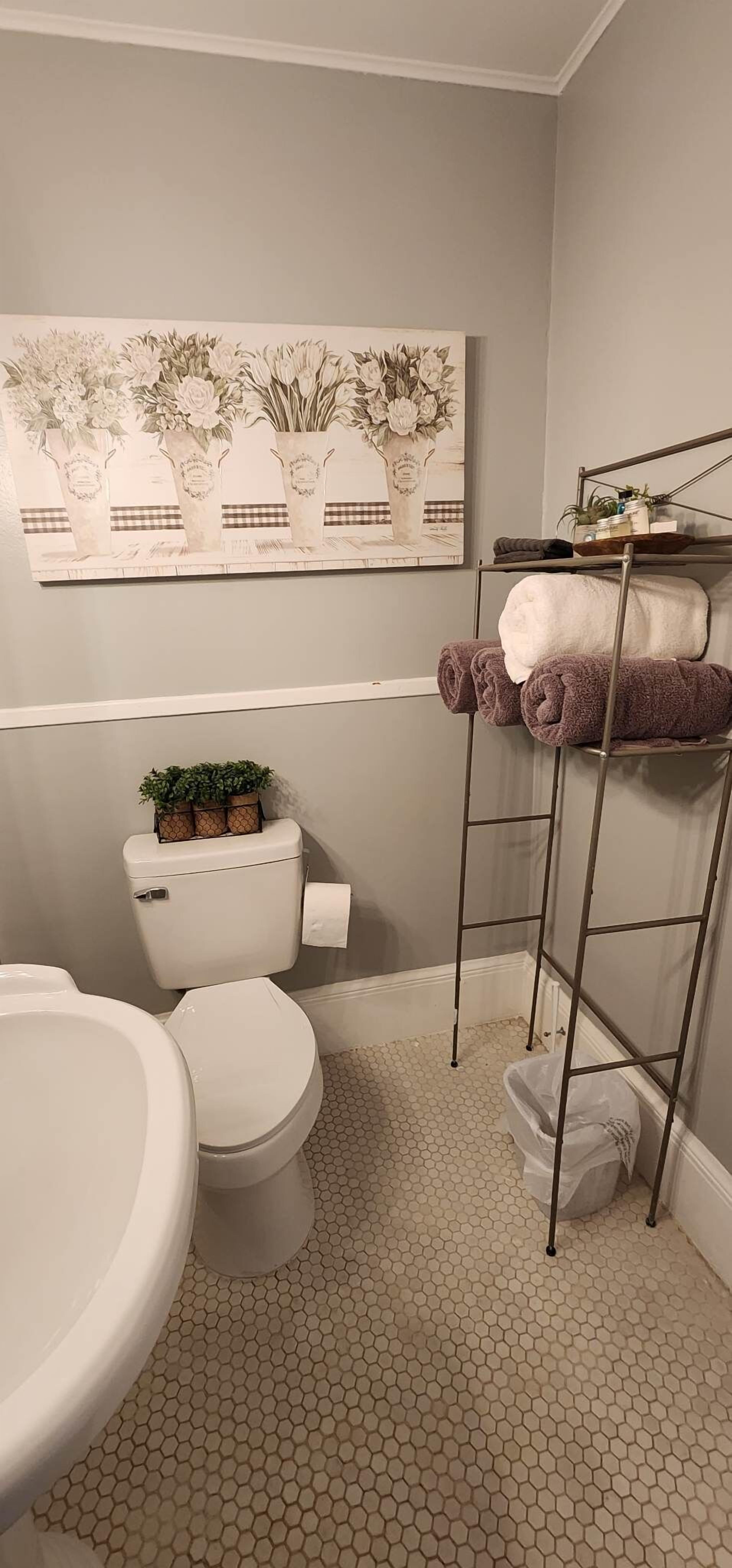 Baño con inodoro, lavabo y toallero con toallas.