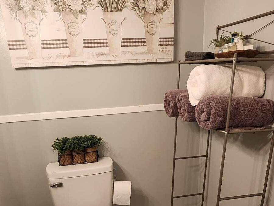 Baño con inodoro, lavabo y toallero con toallas.