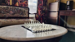 A chessboard on a marble table in a room with a floral sofa and curtains. - The Clinton Inn (Clinton)