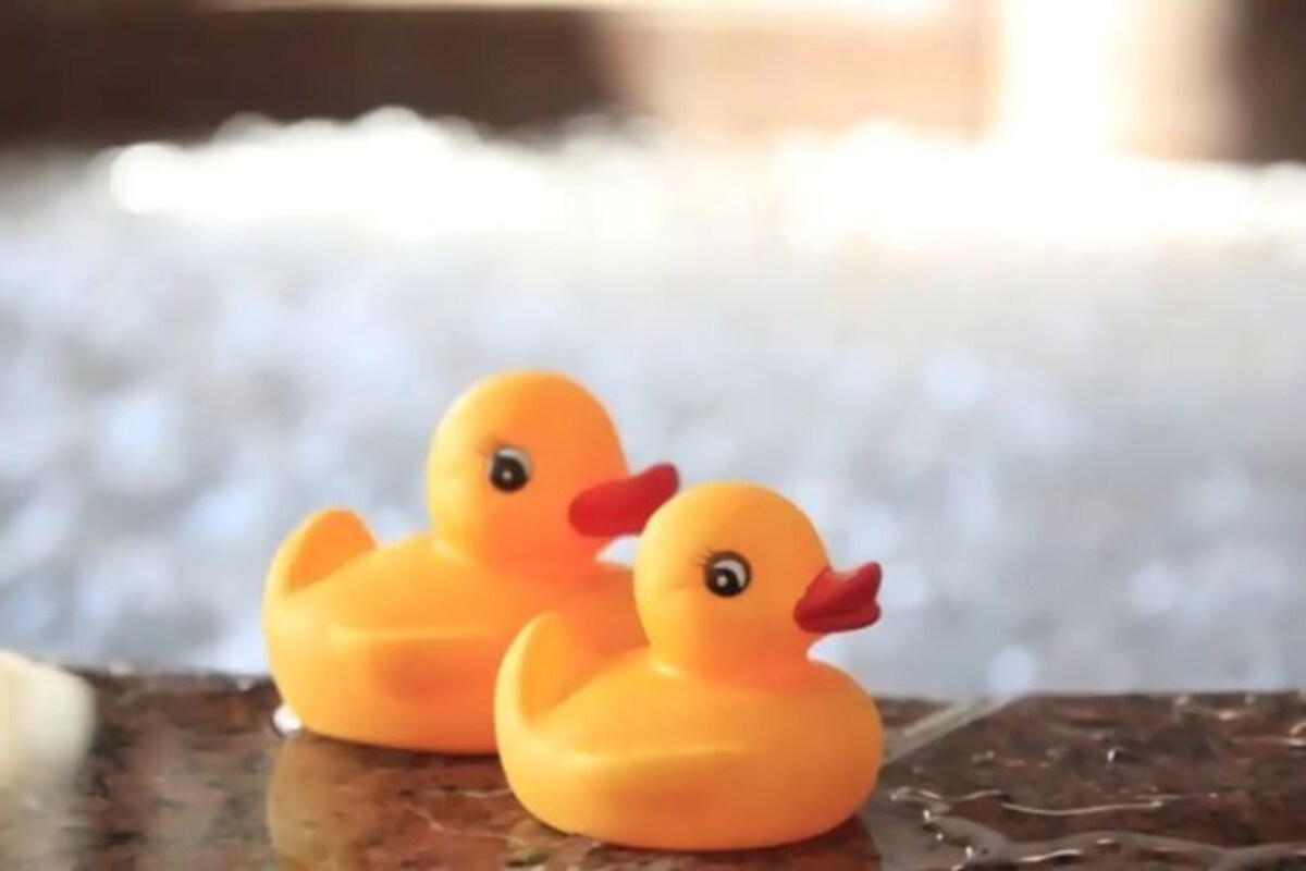 Two rubber ducks on a reflective surface.