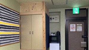 A room with a wooden wardrobe, a refrigerator, a microwave, and a door with a no-smoking sign. - HOTEL PRELE SHINKAN (Tokyo)