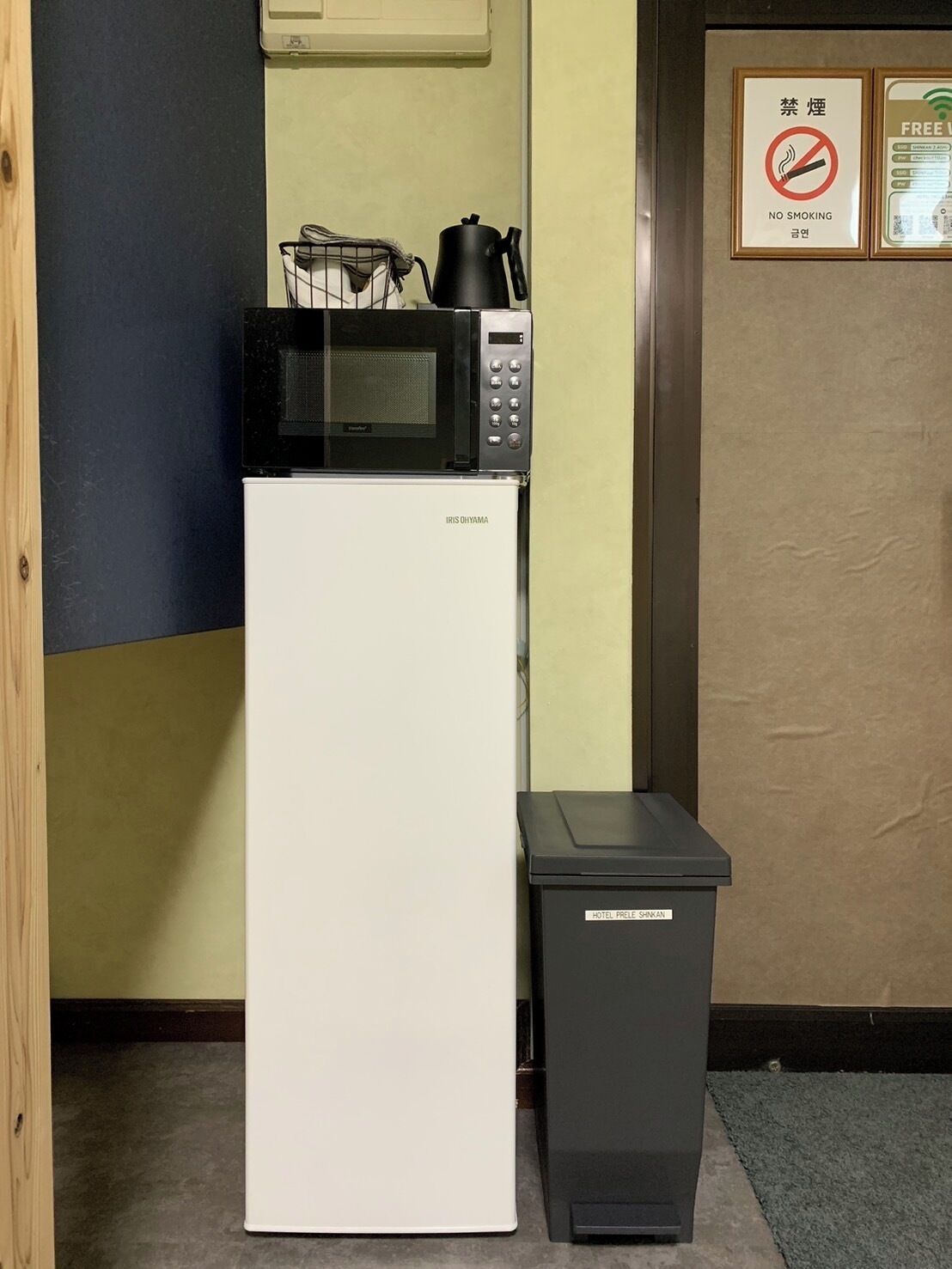A compact kitchen with a microwave and a small trash bin.