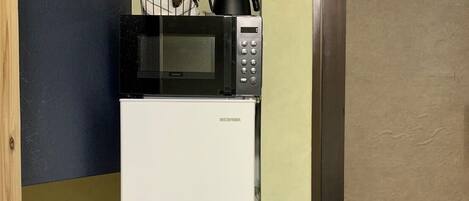 A compact kitchen with a microwave and a small trash bin.