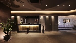 A modern hotel lobby with a reception desk, a staff-only door, and a seating area with a view of the interior. - Doutonbori Crystal Hotel IV (Osaka)