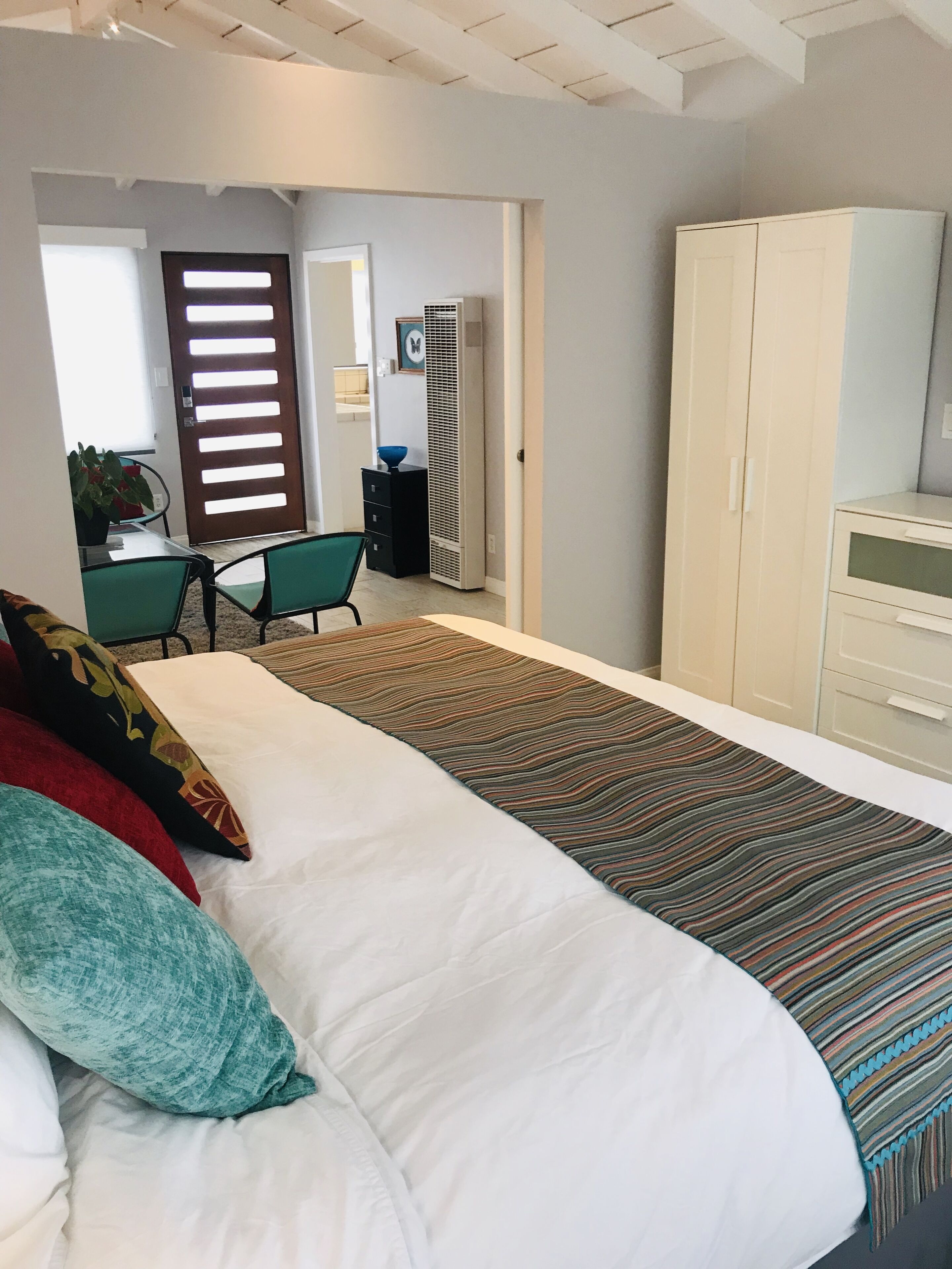 Ein Schlafzimmer mit Bett, Schreibtisch, Stuhl, Kleiderschrank und Heizkörper.