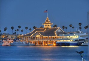 A waterfront building with a prominent tower, surrounded by palm trees and boats.