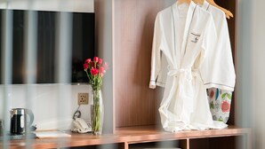 A wooden desk with a white robe, a vase with red flowers, a telephone, and a kettle. - Orussey One Boutique (Phnom Penh)