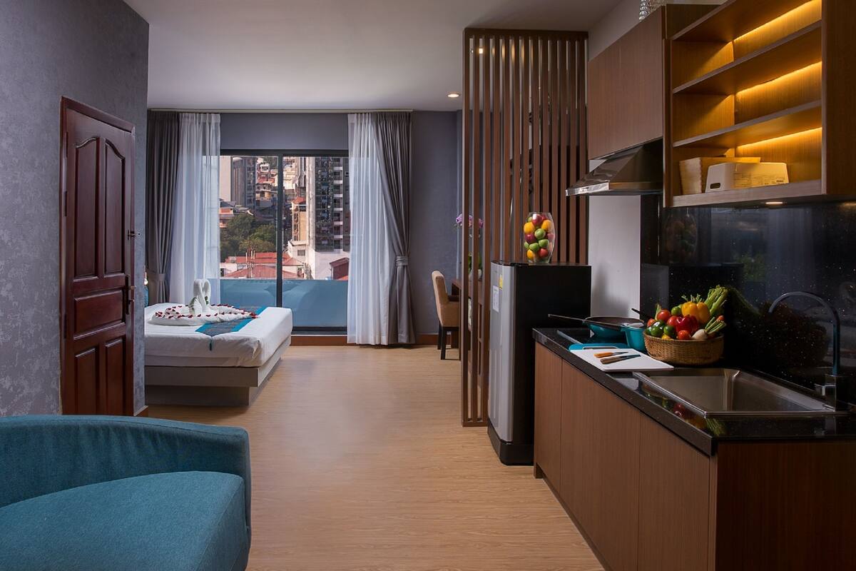 Ein modernes Hotelzimmer mit Balkon, einer Küchenzeile und einem Sofa.
