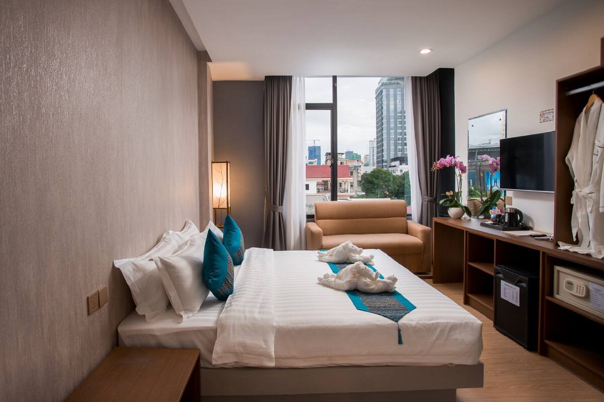 Ein Hotelzimmer mit Bett, Schreibtisch, Stuhl, Fernseher und Blick auf die Stadt.