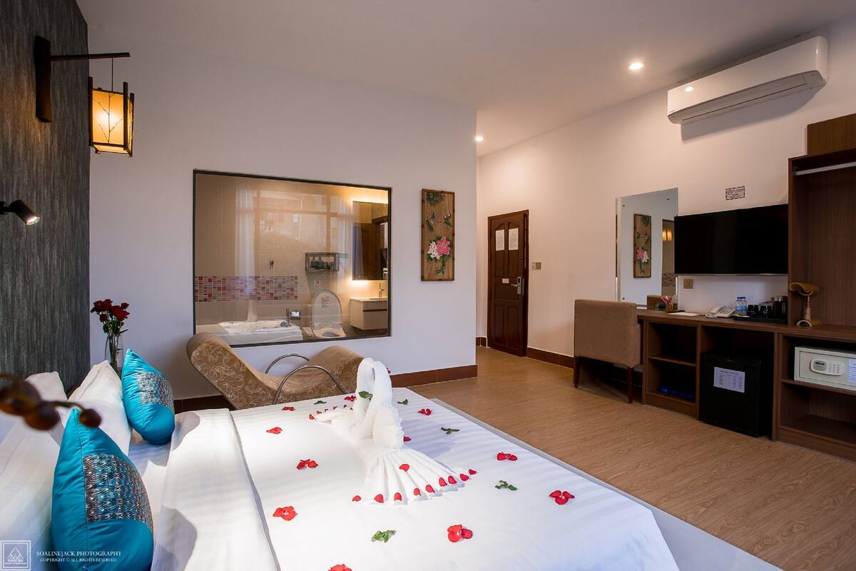 Ein Hotelzimmer mit Bett, Schreibtisch, Stuhl, Spiegel und Klimaanlage.