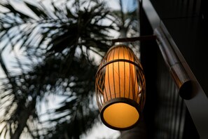 A hanging lamp with a warm light against a blurred background of trees.