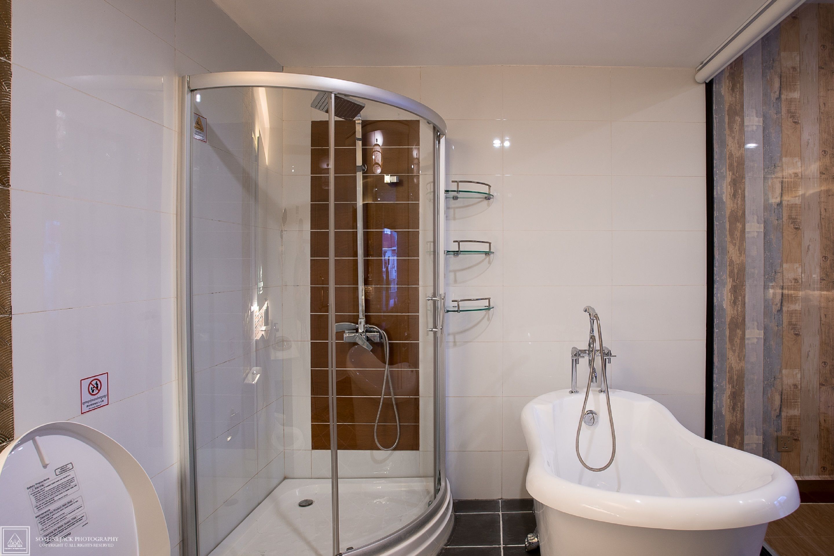 A modern bathroom with a glass-enclosed shower, a freestanding bathtub, and a tiled wall.