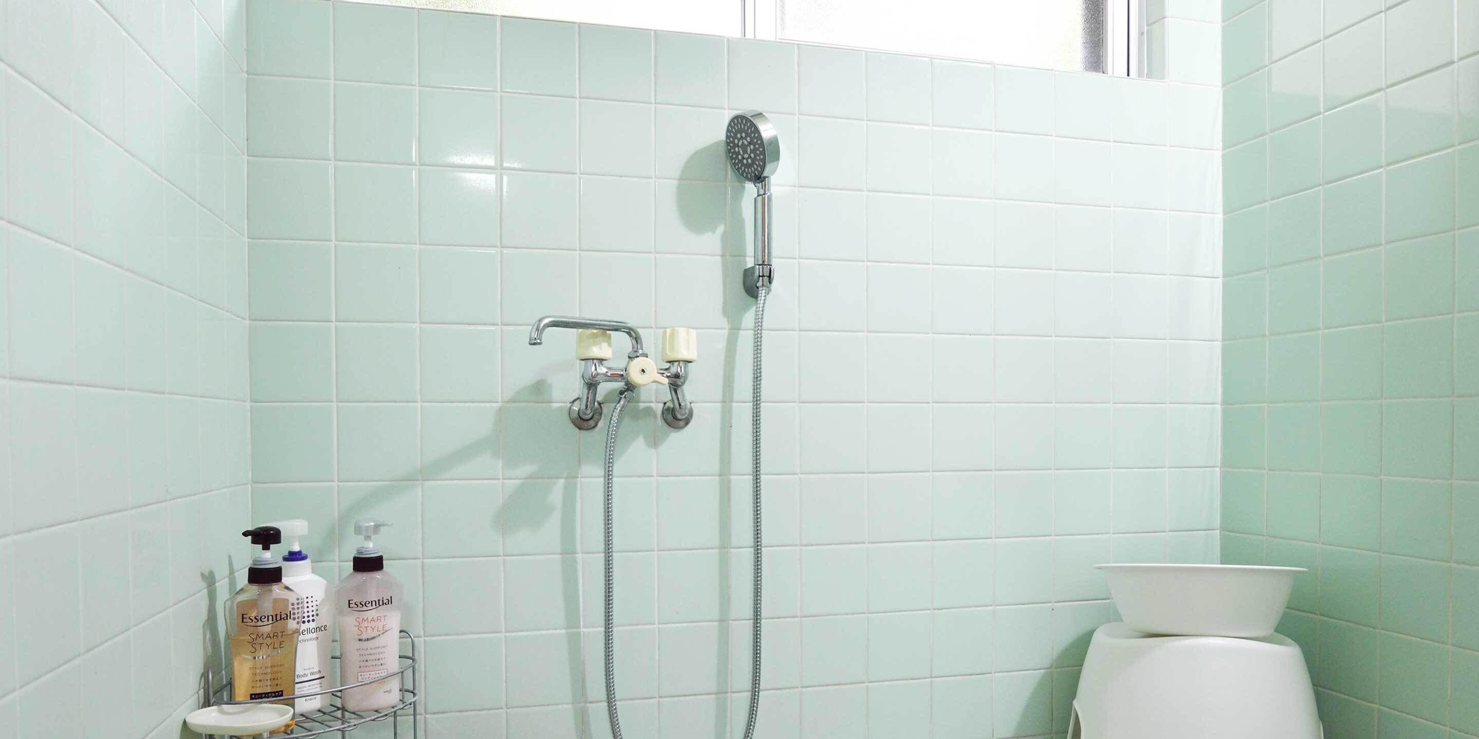 A bathroom with a shower, a toilet, and a shelf with toiletries.