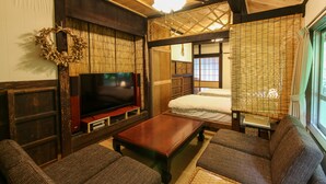 A traditional Japanese-style room with tatami flooring, a television, a wooden coffee table, and a futon bed. - #Nerome01 Traditional Okinawan House in YAMBARU, eg  (Ogimi)