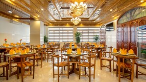 A spacious restaurant with wooden furniture, chandeliers, and large windows allowing natural light.