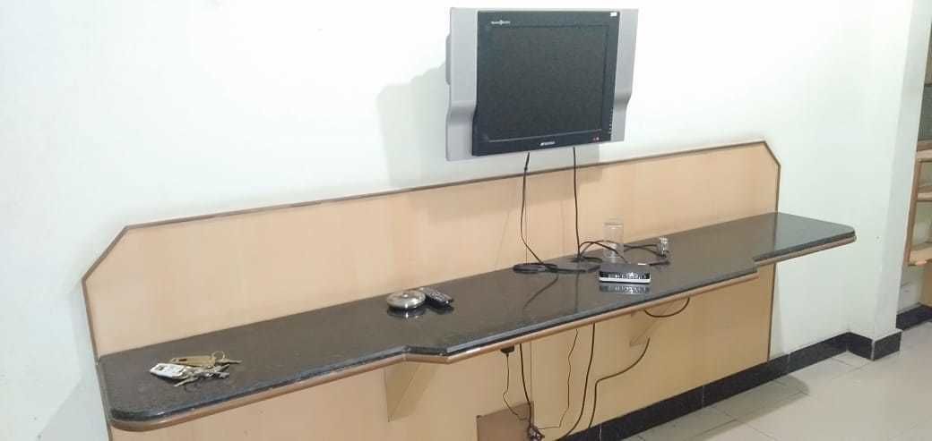 A reception desk with a flat-screen monitor, a telephone, and a set of keys on the counter.