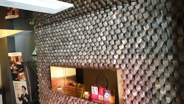 A wall with a honeycomb pattern and a glass display case with items inside.