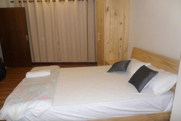 A single bed with a wooden headboard, a white bedspread, and two pillows. - Heritage De Patan (Lalitpur)
