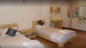 A room with two single beds, wooden headboards, bedside tables, and a small wooden dresser. - Heritage De Patan (Lalitpur)