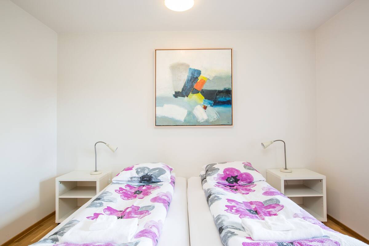A twin bedroom with two single beds, each with a nightstand and a desk lamp.