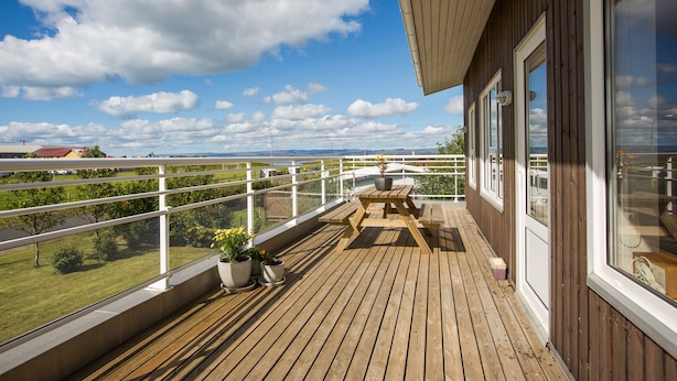 Eine Holzterrasse mit Tisch und Stühlen, Blumentöpfen und Blick auf die Landschaft.