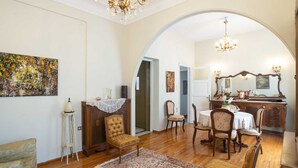 A spacious living room with a wooden floor, a dining area with a table and chairs, and a kitchen area with a wooden counter and a mirror. - Classic Central Athinian Apartment (Athens)